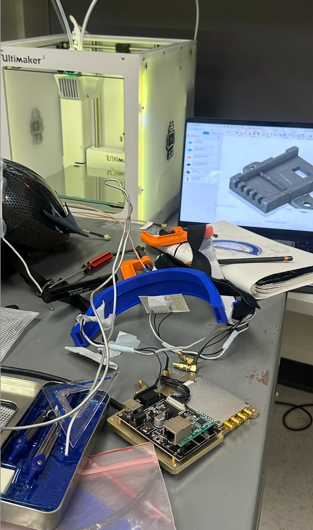 RMG wearable assembly, printed mounts, CAD model, and radio hardware on the laboratory workbench